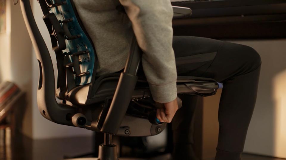 Vidéo prise en gros plan du flanc du fauteuil de jeu Embody, avec une personne ajustant le mécanisme de réglage de hauteur de l’assise réglable