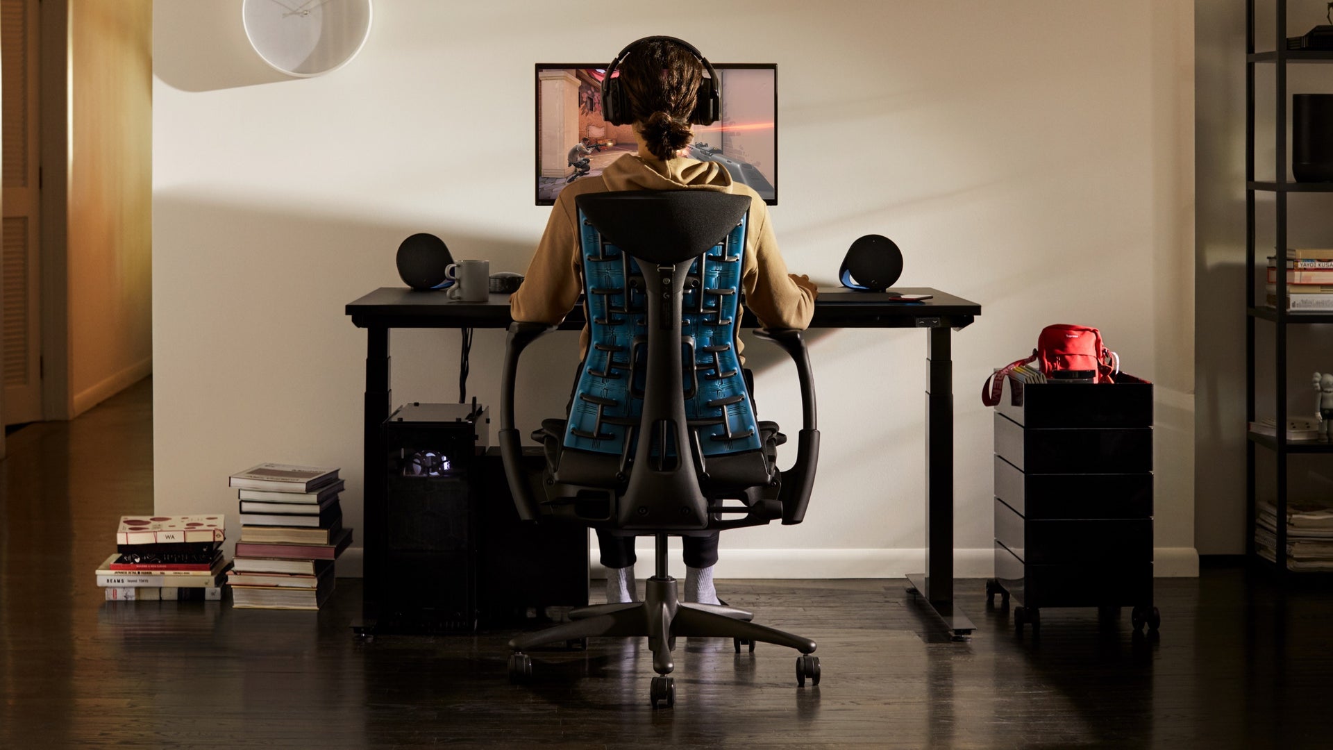 Personne installée dans un fauteuil de jeu Embody, les yeux rivés sur un écran fixé au support d'écran Ollin monté sur la surface du bureau de jeu, le tout dans un environnement domestique.